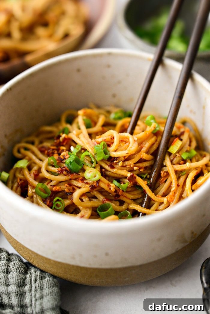 Fiery Garlic Sesame Noodles 18 A close-up shot of saucy Spicy Garlic Sesame Noodles, highlighting the texture of the noodles and the rich coating of the sauce.