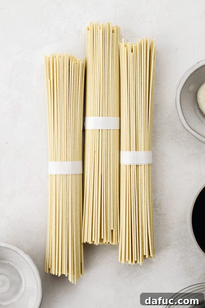Fiery Garlic Sesame Noodles 5 Uncooked lo mein egg noodles arranged on a cutting board, ready for the boiling pot.