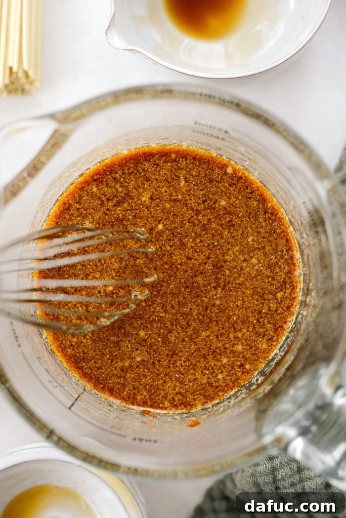 Fiery Garlic Sesame Noodles 10 A whisk vigorously combining all the sauce ingredients in a bowl until smooth and cohesive.