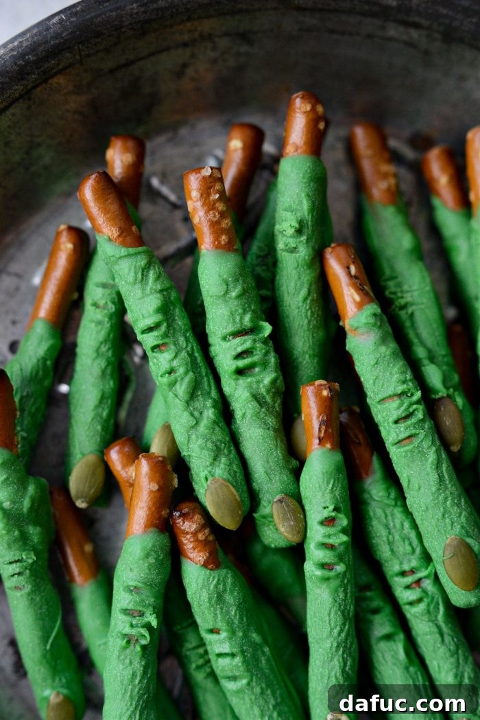 Ghoulish Grabbers 2 Deliciously green witch finger pretzels with pumpkin seed nails, arranged on a serving platter for Halloween.