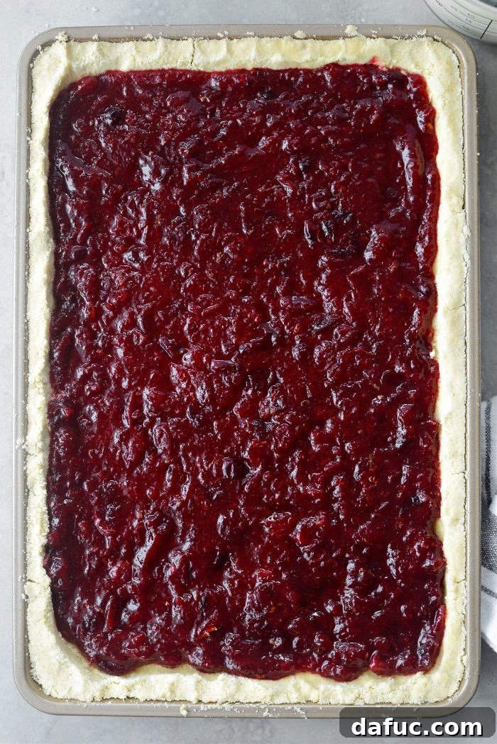 Crimson Kitchen 15 Cranberry filling spread evenly over the partially baked crust in a jelly roll pan, ready for the sour cream topping.