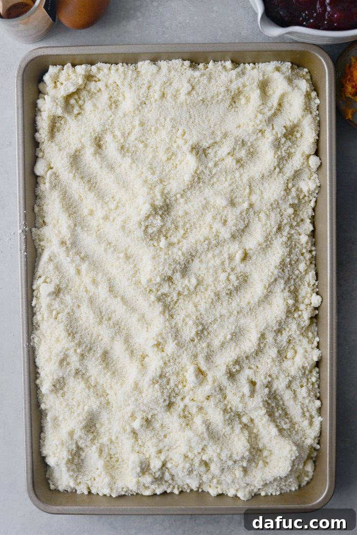 Crimson Kitchen 7 Transferring the crumbly cake mix and butter mixture into a 10x15 jelly roll pan to form the crust of the Cranberry Küchen.