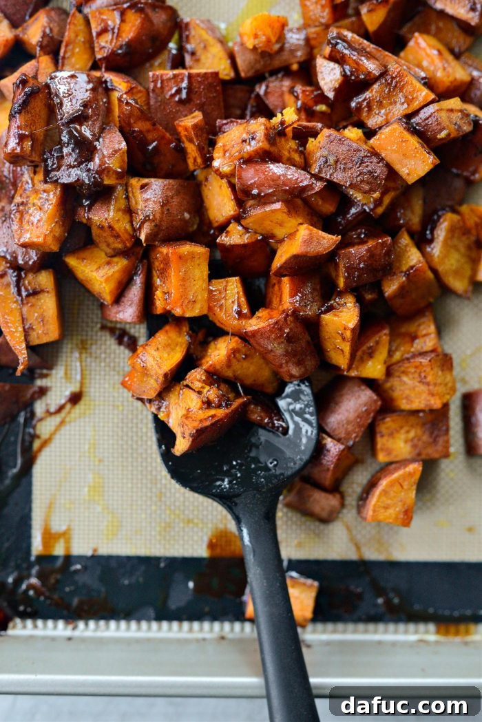 Freshly roasted sweet potatoes being tossed one last time in their sticky glaze on the baking sheet