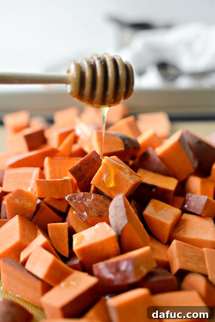 Garlic hot honey being drizzled over seasoned sweet potatoes