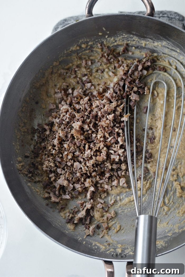 Cooking the roux, a mixture of flour and fat, in a skillet while whisking