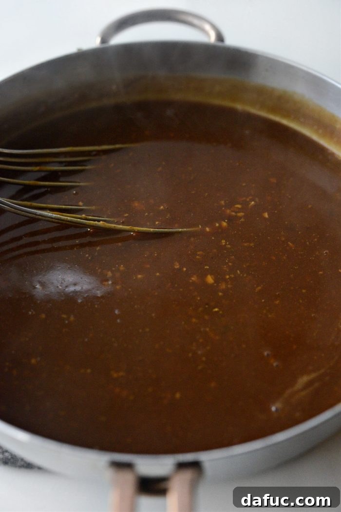 Slowly whisking the giblet stock into the roux to create a lump-free gravy