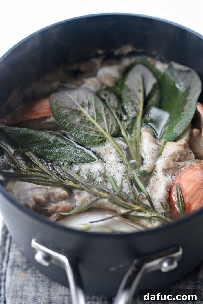 Water being poured over turkey giblets and herbs in a saucepan for stock
