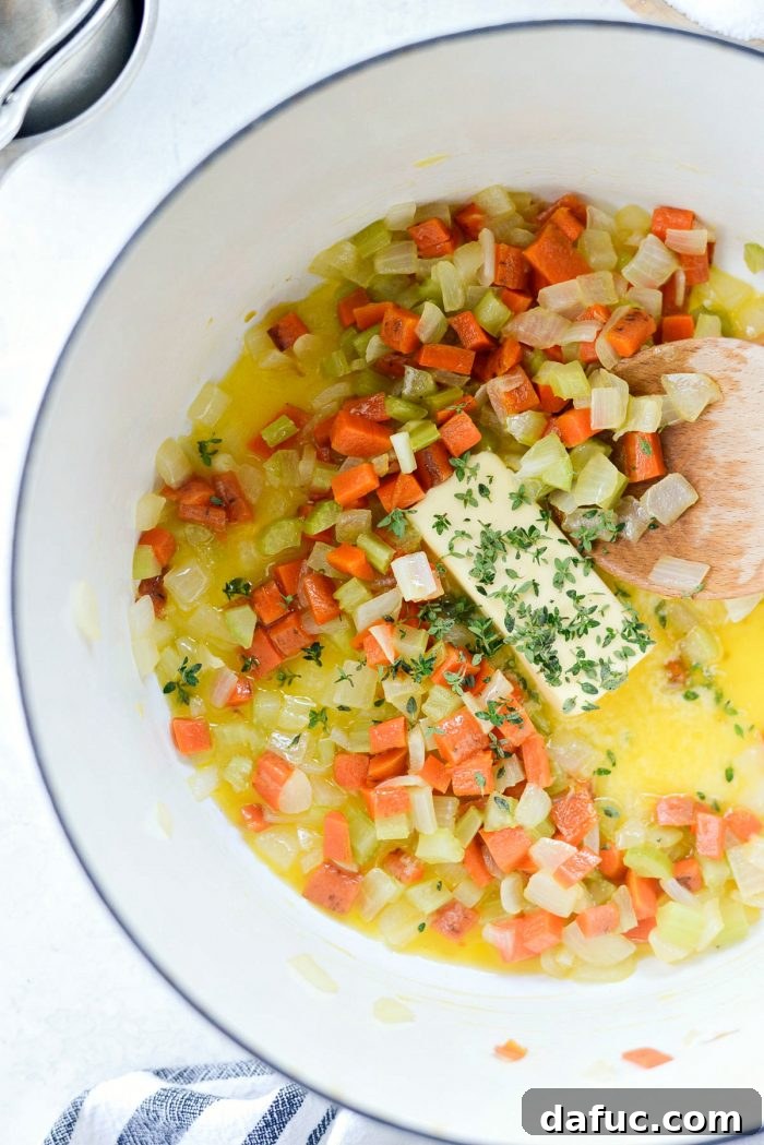 Softened vegetables in a pot with more butter and fresh thyme being added.