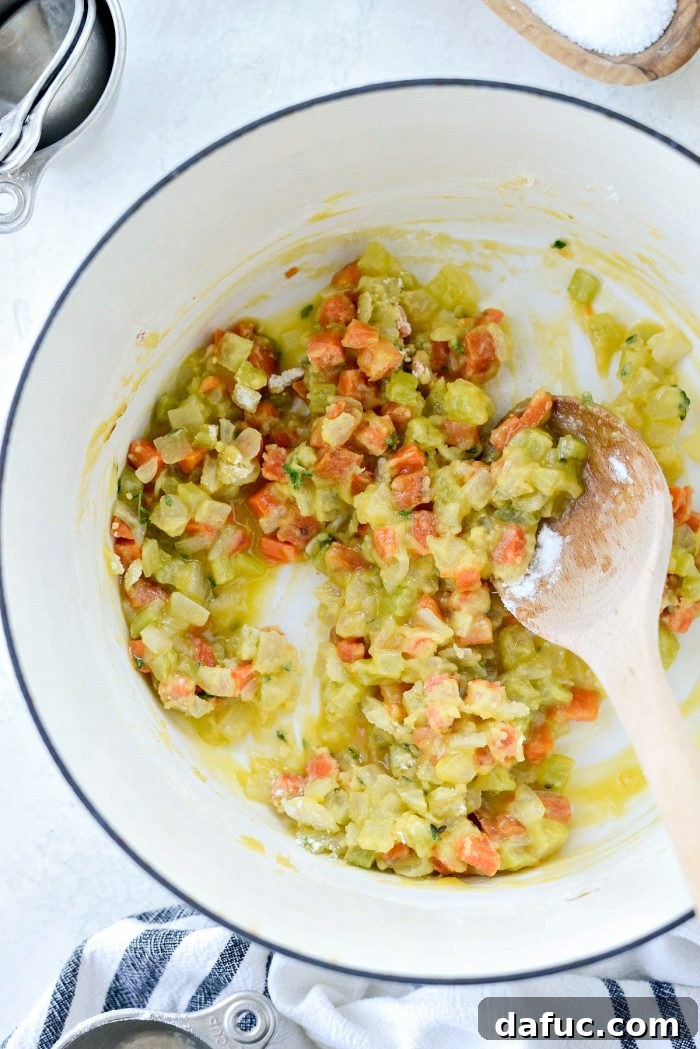 Flour being stirred into the butter and vegetable mixture to form a roux.