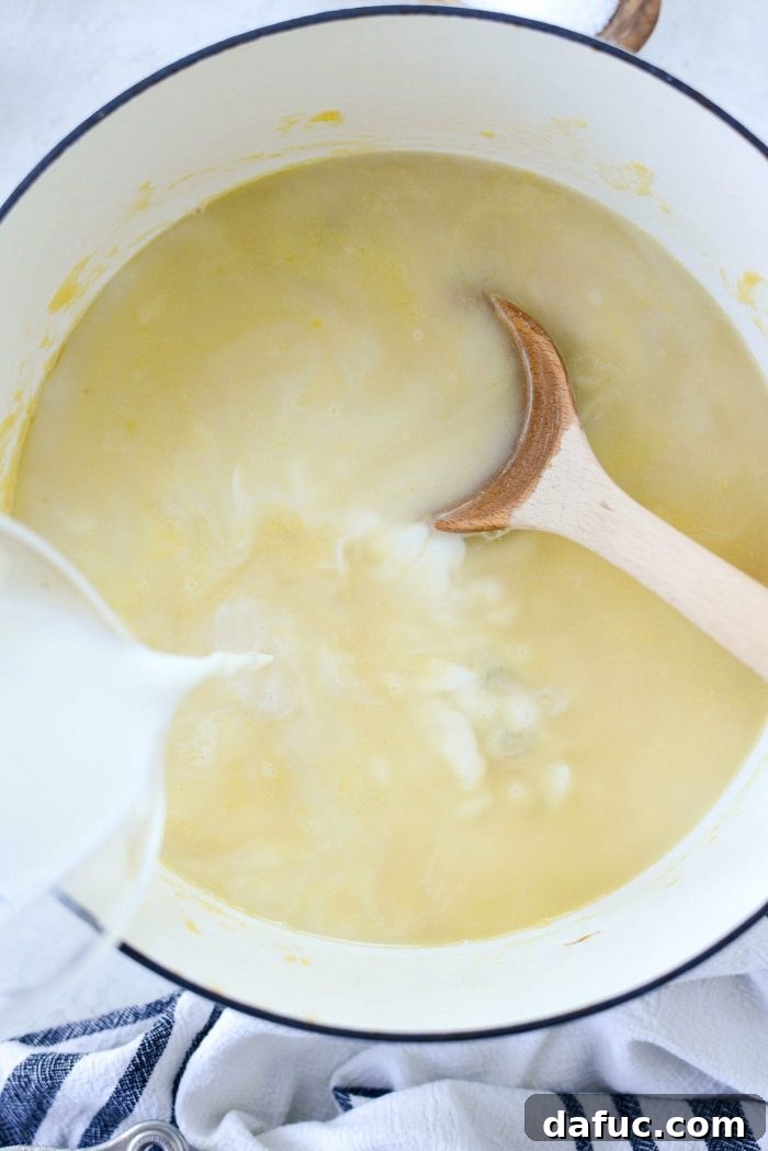 Chicken broth being poured into the roux and vegetable mixture.