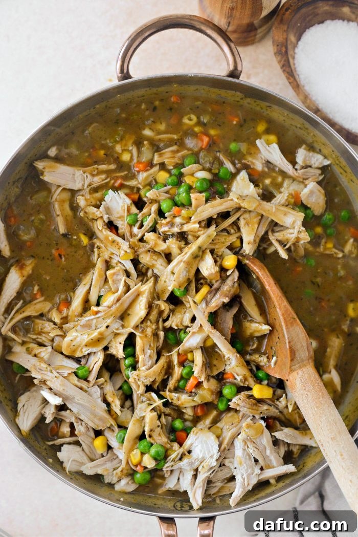 Stirring turkey and vegetables to combine thoroughly in the pie filling mixture