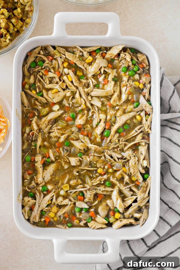 Transferring the rich turkey mixture to a casserole dish, spreading it evenly for layering