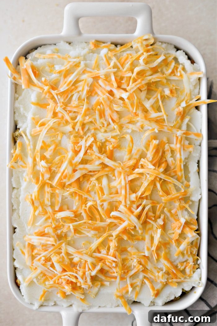 Topping the shepherd's pie with shredded cheddar jack cheese for a golden, bubbly crust