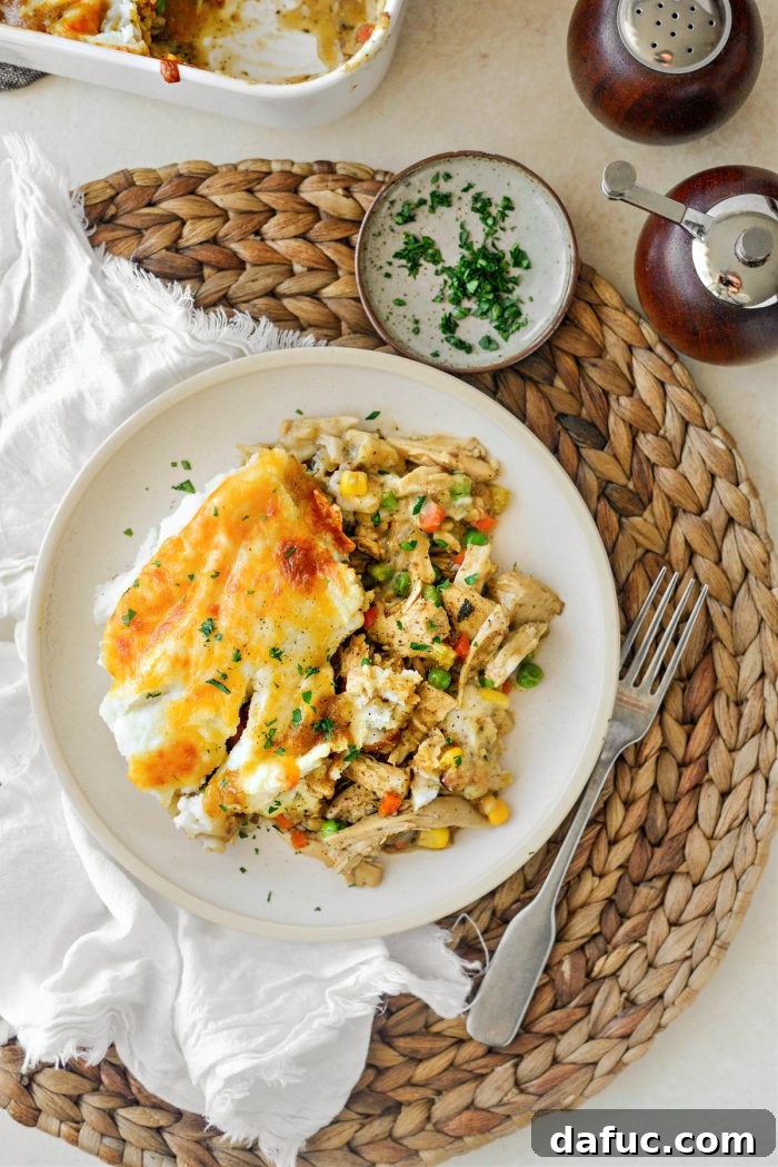 Serving spoonfuls of Leftover Turkey Shepherd's Pie Casserole onto individual plates, garnished with parsley