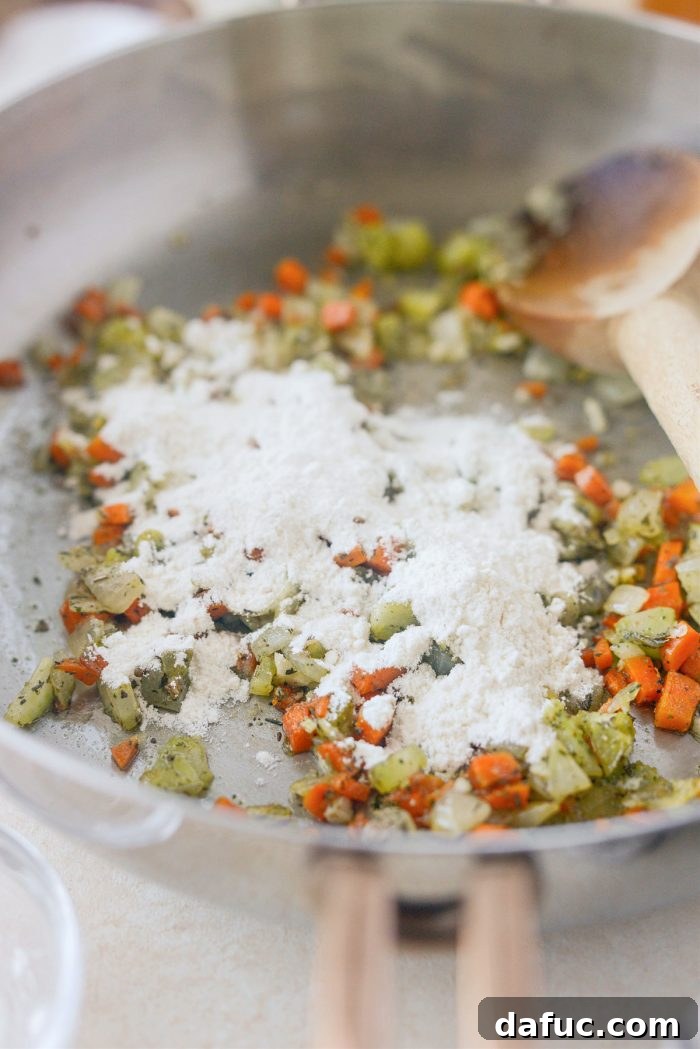 Sprinkling all-purpose flour over sautéed vegetables to create a roux for the turkey pie filling