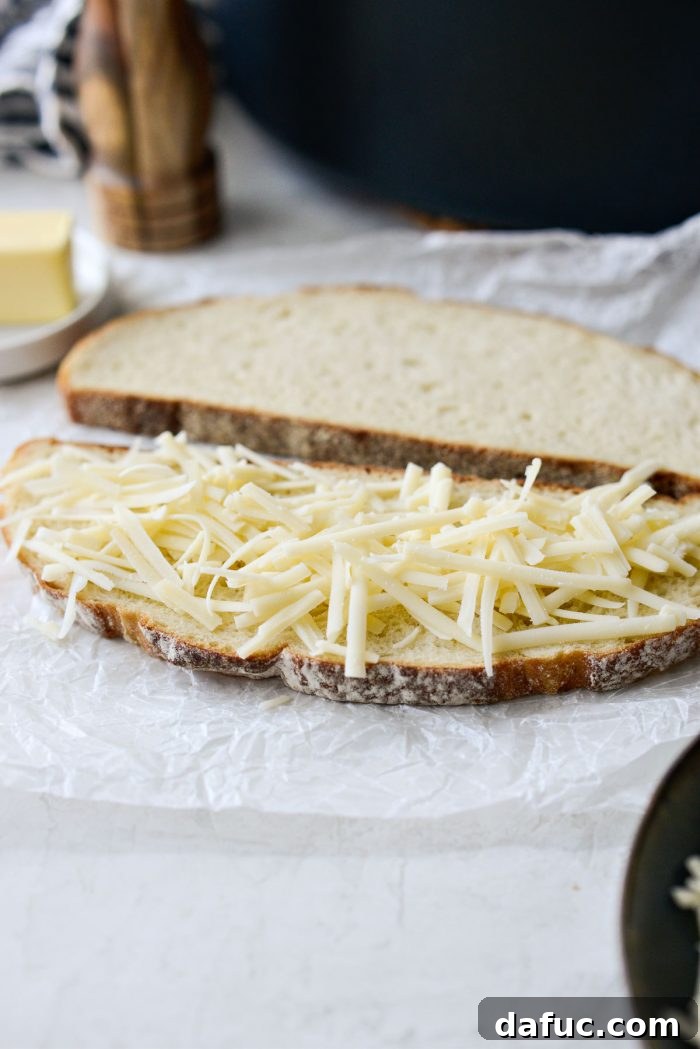 Slice of sourdough bread topped with shredded Gruyère cheese