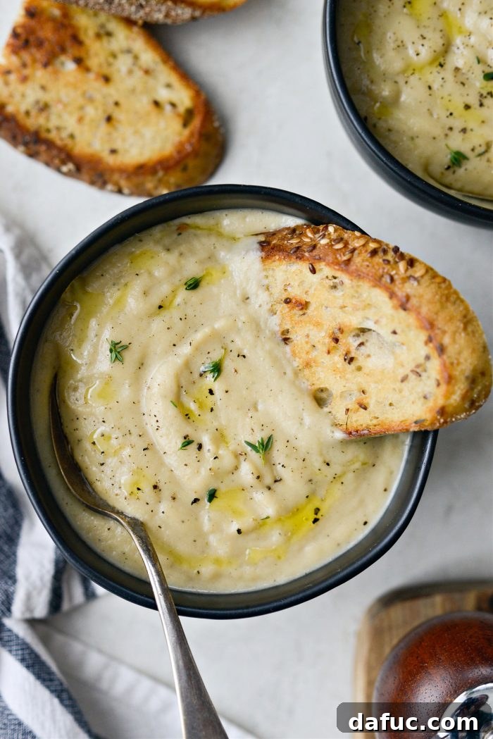 Golden Roasted Parsnip Puree 2 Creamy Roasted Parsnip Soup served in a bowl, garnished with a drizzle of olive oil and fresh herbs, next to grilled bread.