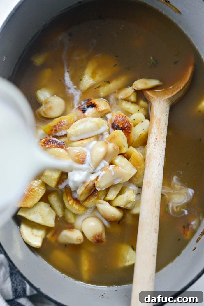 Golden Roasted Parsnip Puree 15 Pouring broth and milk into the Dutch oven with roasted vegetables and herbs.