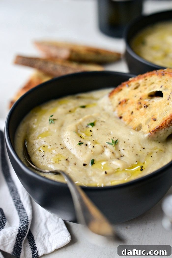 Golden Roasted Parsnip Puree 3 A bowl of Creamy Roasted Parsnip Soup with a spoonful taken out, showing its smooth texture.