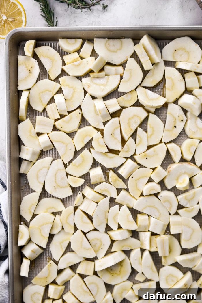 Golden Roasted Parsnip Puree 7 Chopped parsnips evenly spread on a baking sheet after being tossed with oil, honey, salt, and pepper.