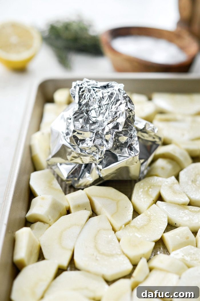 Golden Roasted Parsnip Puree 9 Aluminum foil crimped around garlic cloves to form a pouch, placed on the baking pan with parsnips.