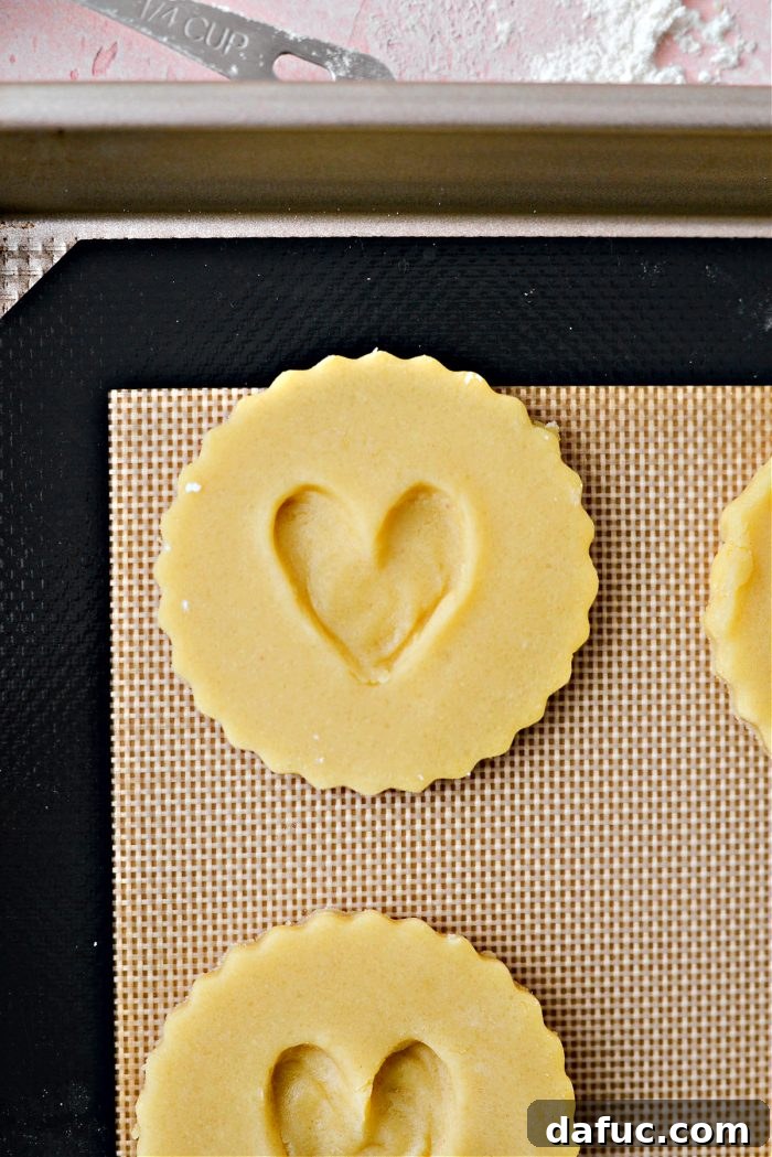 Jam Filled Butter Heart Cookies 12 Using the rounded end of a spoon to press a distinct heart shape into the center of each round cookie on the baking sheet.