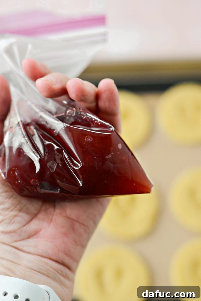 Jam Filled Butter Heart Cookies 13 Seedless raspberry jam being carefully piped from a resealable plastic bag into a small, makeshift piping bag.