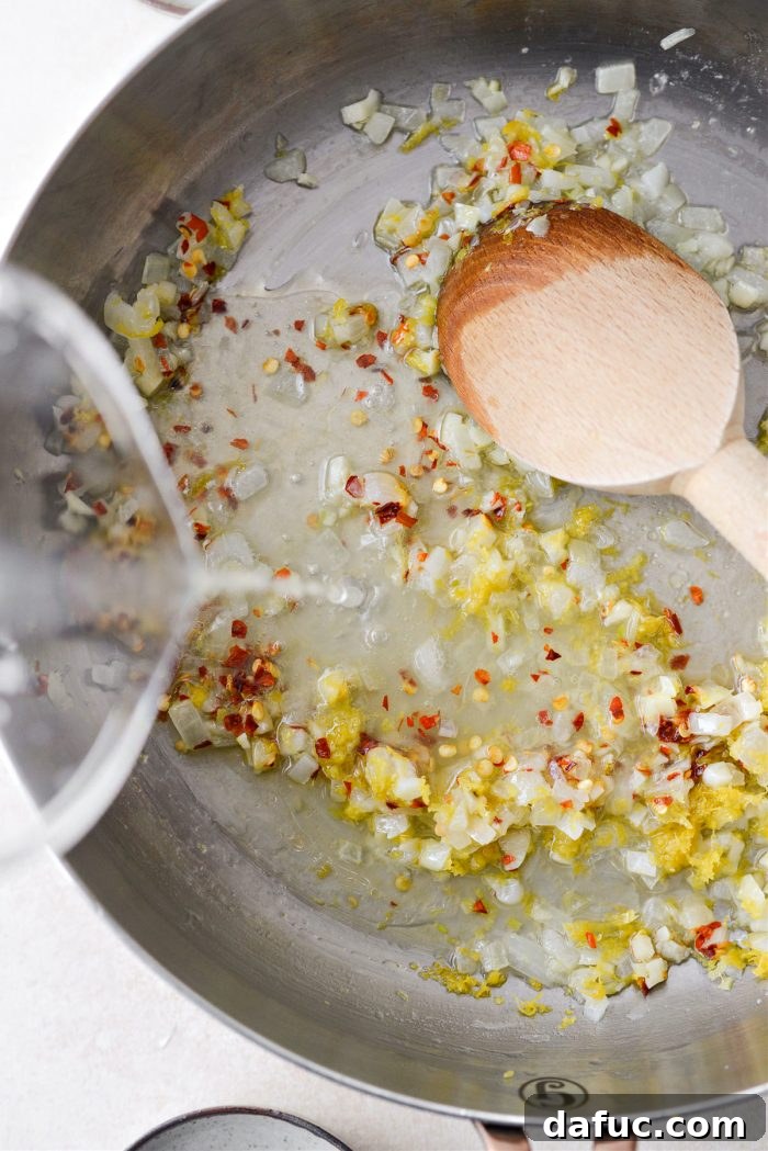 Velvety Lemon Parmesan Pasta 10 Lemon juice being poured into the skillet with sautéed aromatics