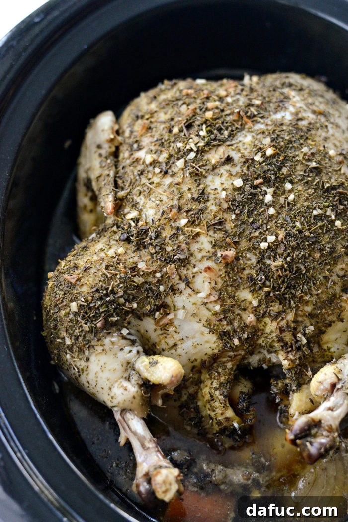 Fall-Off-The-Bone Slow Cooker Chicken 3 A whole slow cooker chicken on a bed of vegetables