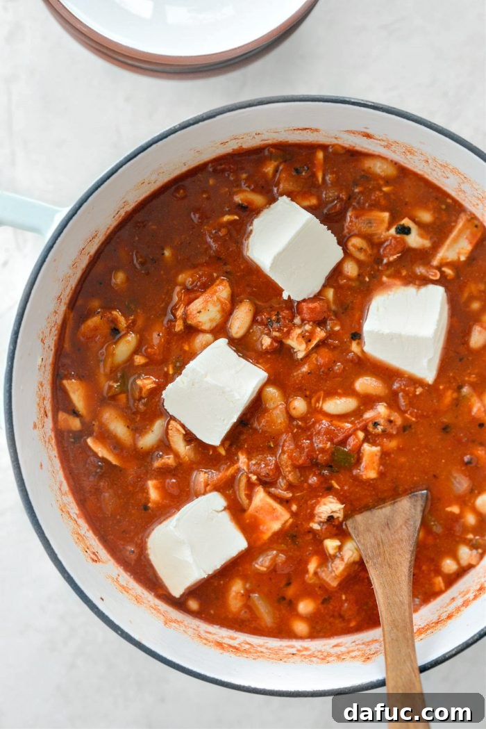 Zesty Buffalo Chicken Chili 14 Cream cheese being added to the simmering chili