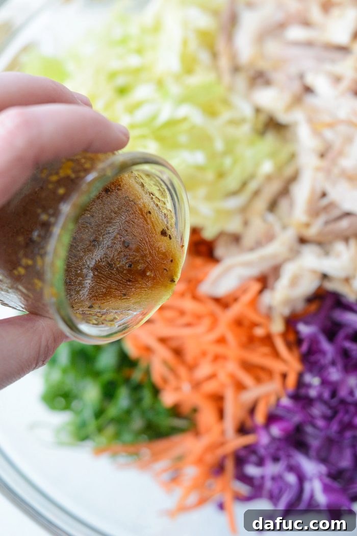 Crunchy Asian Chicken Salad 9 Pouring the homemade ginger dressing over the prepared salad ingredients