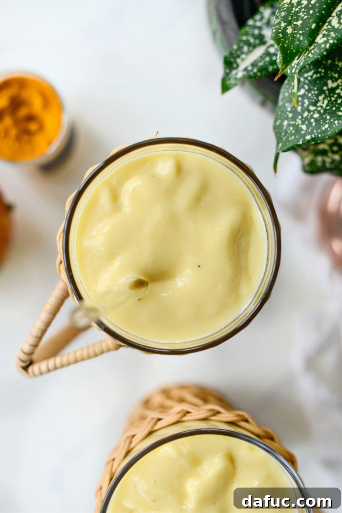 Liquid Sunshine Mango 14 A close-up of the Golden Hour Mango Smoothie, highlighting its vibrant color and smooth texture, with a straw.
