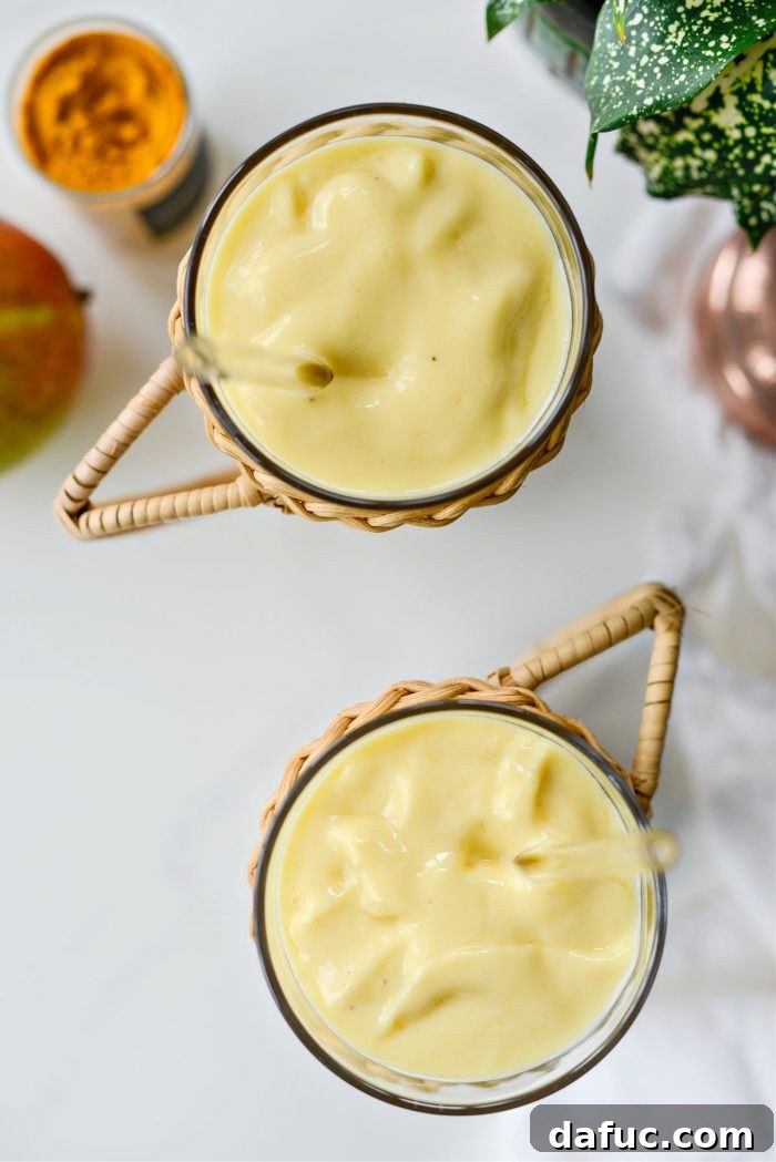 Liquid Sunshine Mango 3 Golden Hour Mango Smoothie in a tall glass with fresh mango slices on the rim, set against a bright, sunny background.