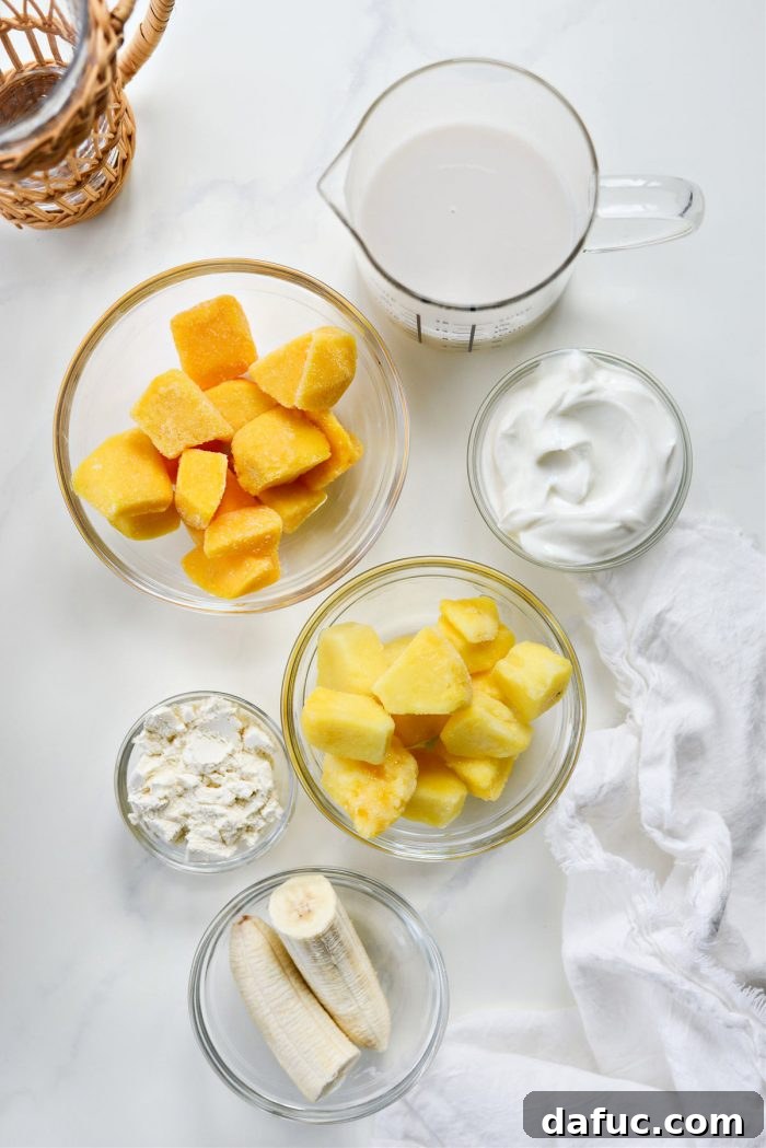 Liquid Sunshine Mango 4 Ingredients for the Golden Hour Mango Smoothie laid out, including frozen fruit, Greek yogurt, macadamia nut milk, and turmeric.