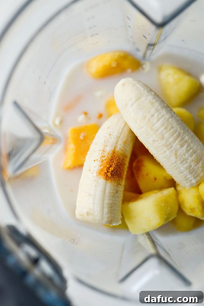Liquid Sunshine Mango 8 Frozen mango, pineapple, banana, and a pinch of turmeric being added to the blender with the liquid ingredients.