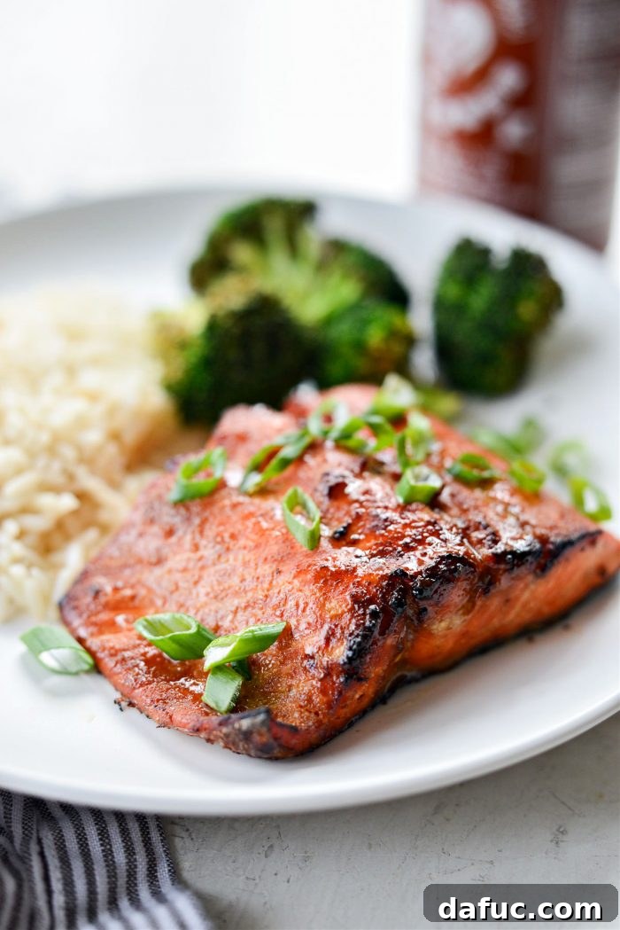 Two pieces of Air Fryer Sriracha Salmon on a plate with garnishes