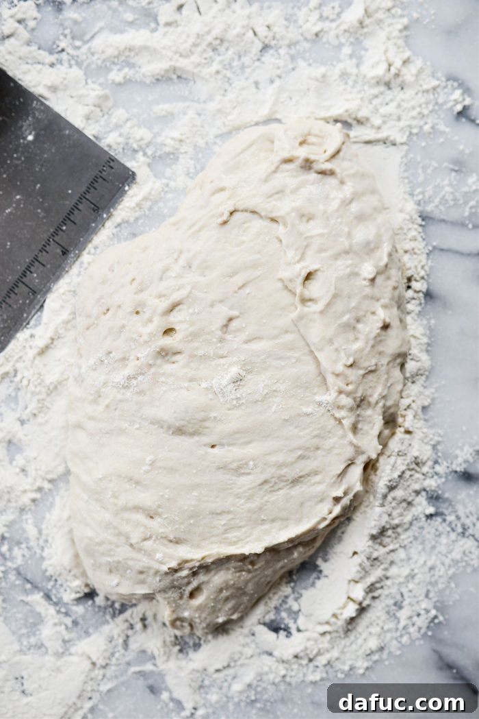 Scraping sticky pizza dough onto a flour-dusted surface