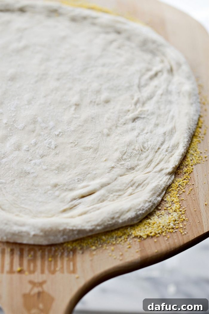 Transferring shaped pizza dough to a cornmeal-dusted pizza peel