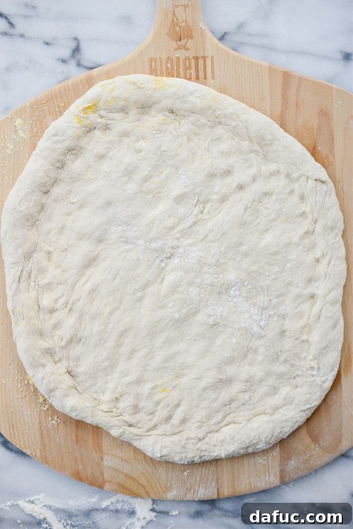 Stretched pizza dough resting on a pizza peel