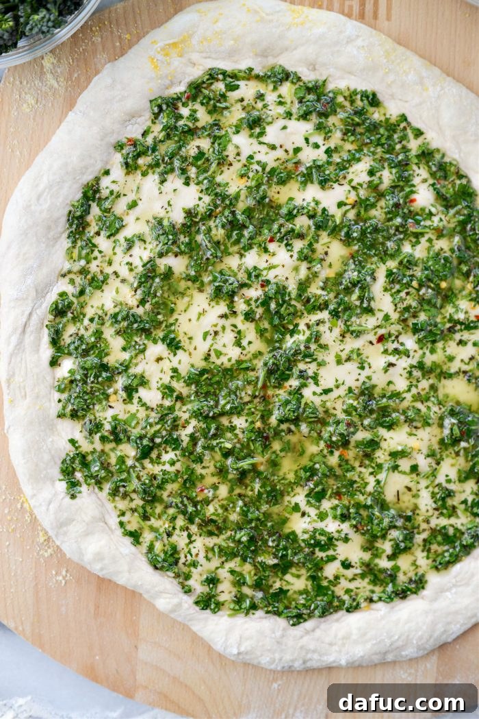 Chimichurri sauce evenly spread over the pizza dough