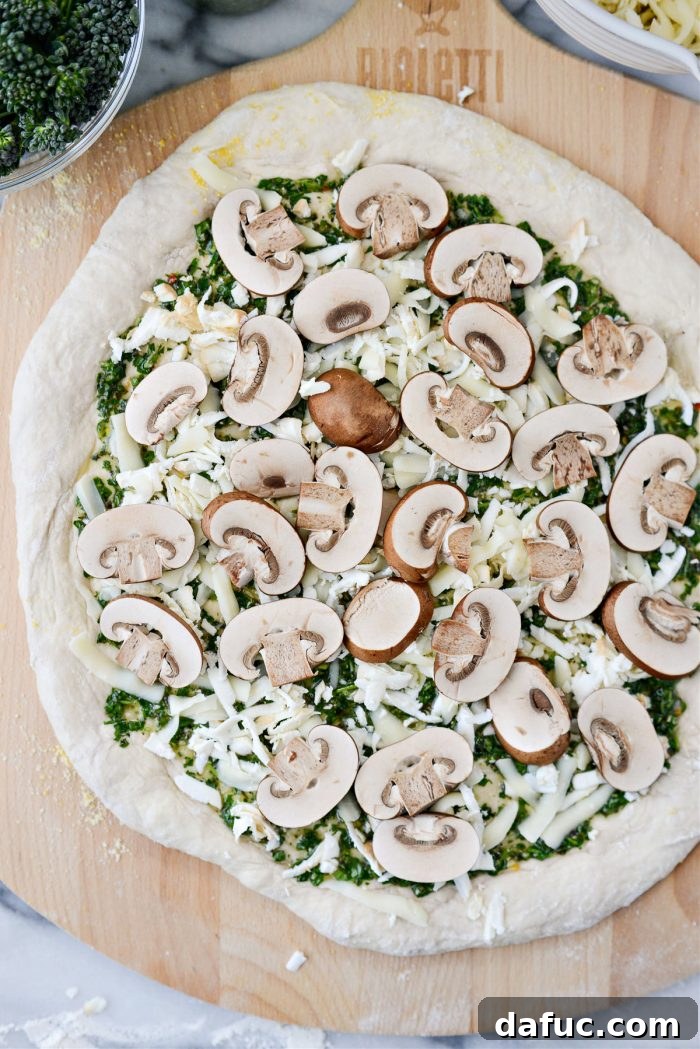 Adding grated cheese to the chimichurri-covered pizza dough