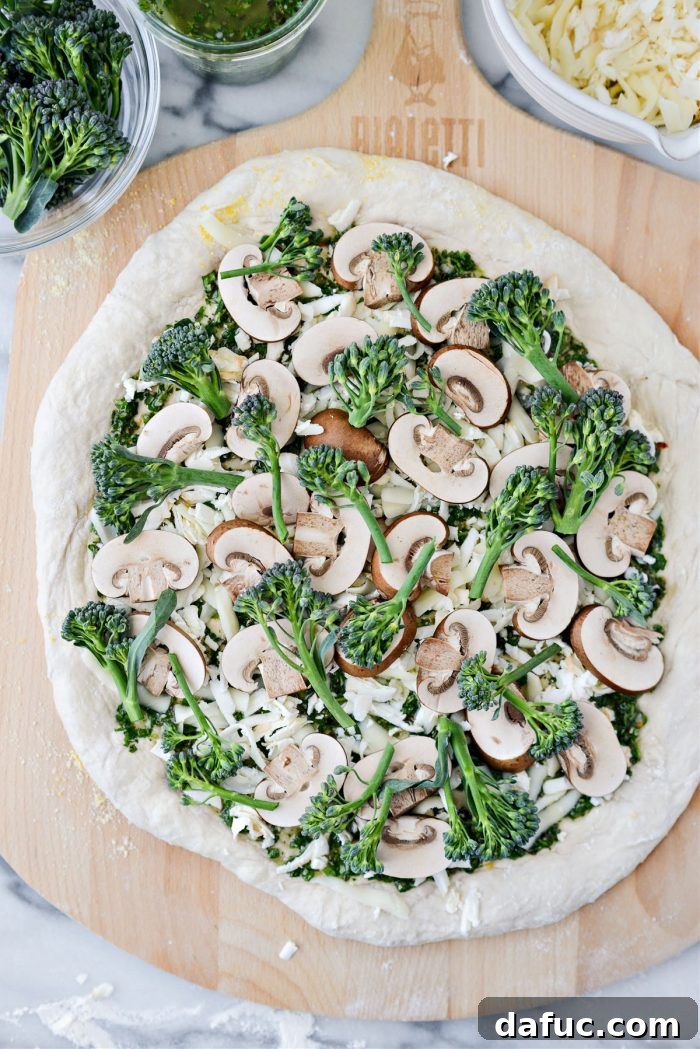 Sliced cremini mushrooms and broccolini being added to the pizza