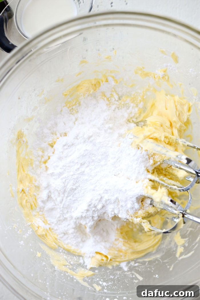 Tangy Lemon Cupcakes with Velvety Frosting 12 Sifted powdered sugar being gradually added to creamed butter in a mixing bowl