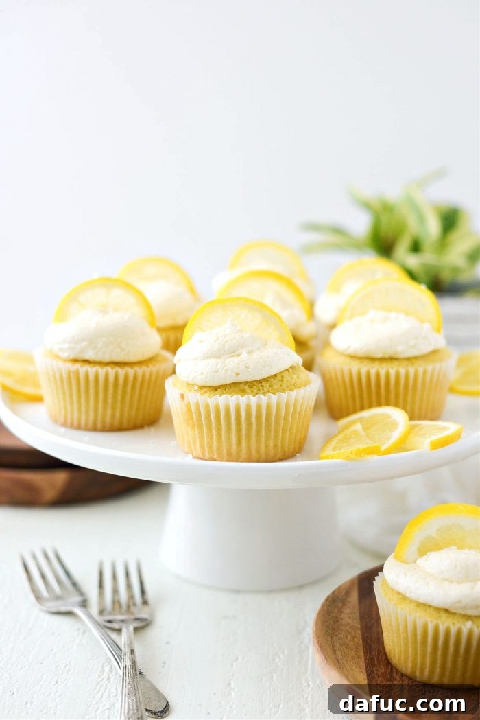 Tangy Lemon Cupcakes with Velvety Frosting 3 Close-up shot of two perfectly frosted lemon cupcakes, garnished with a thin lemon slice