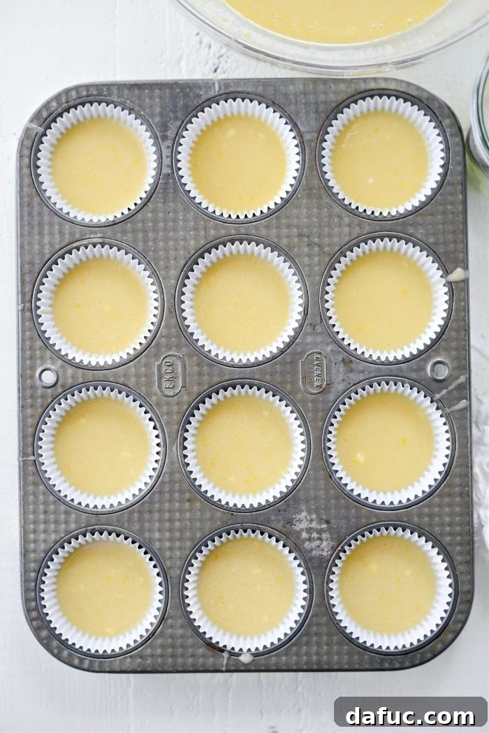 Tangy Lemon Cupcakes with Velvety Frosting 9 Cupcake liners in a muffin tin being filled with precisely 3 tablespoons of lemon cake batter