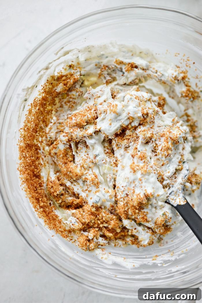 Stirring the panko breadcrumbs into the dip mixture for a final mix