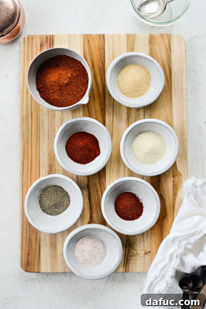A vibrant array of seven different spices laid out on a clean surface, ready for mixing to create street taco seasoning.
