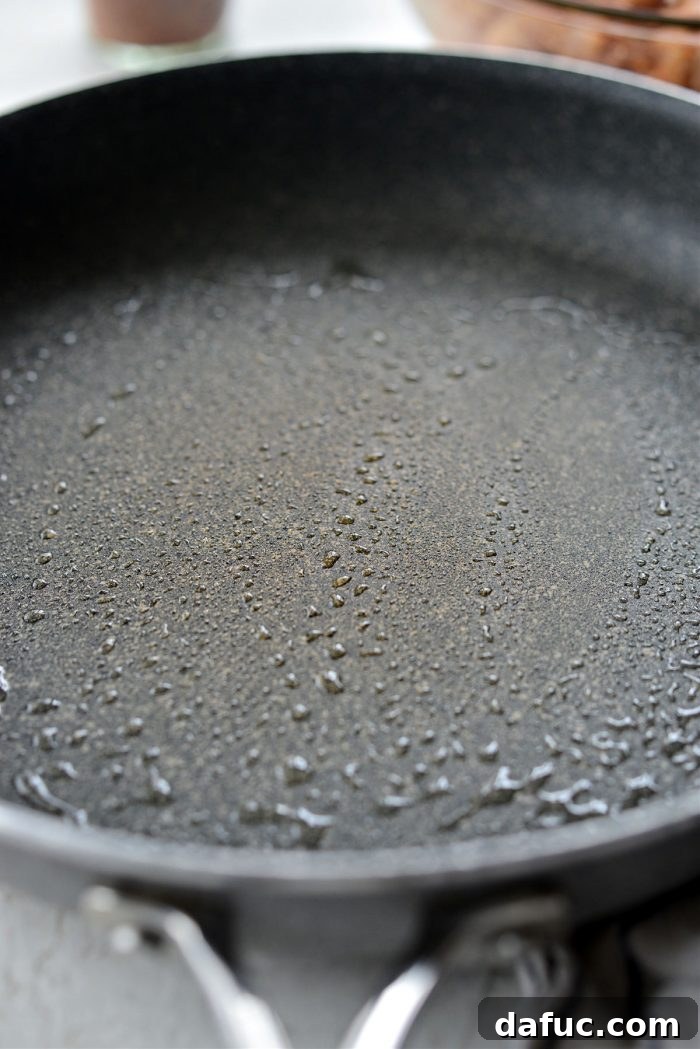 Spraying a nonstick skillet with olive oil spray before cooking the chicken