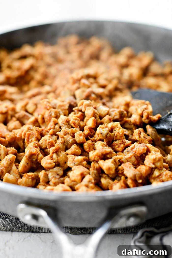 Minced chicken cooking in a skillet until it is no longer pink and is browned in spots