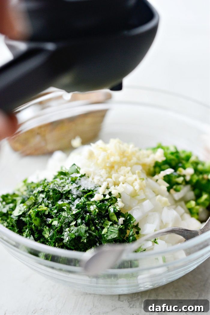Squeezing fresh lime juice over a bowl of diced onion, jalapeño, garlic, and cilantro